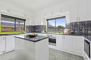 Una cocina moderna con armarios blancos, una isla central y un salpicadero con diseño.