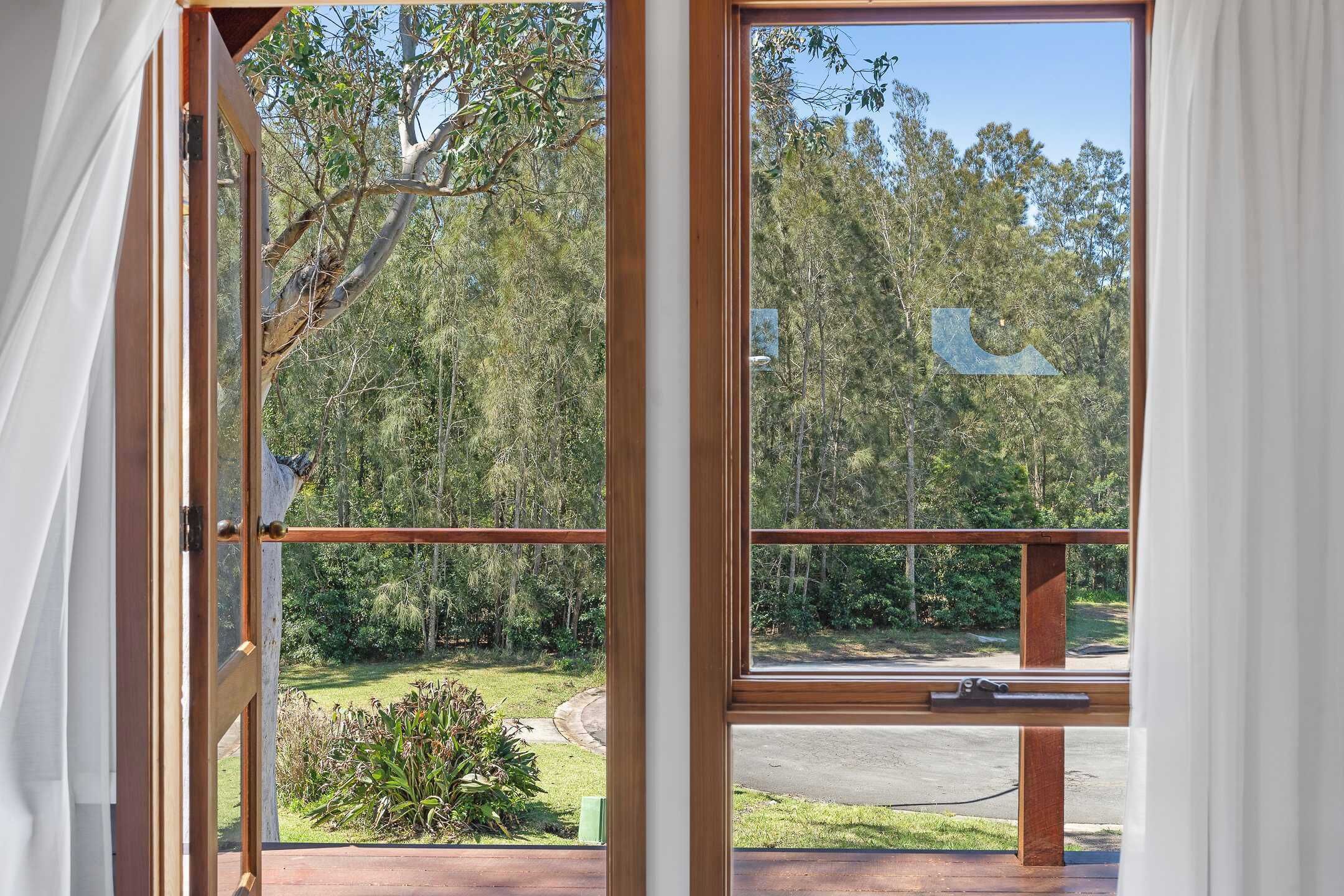 Ein Zimmer mit großem Fenster und Blick auf bewaldetes Gelände und eine Straße.