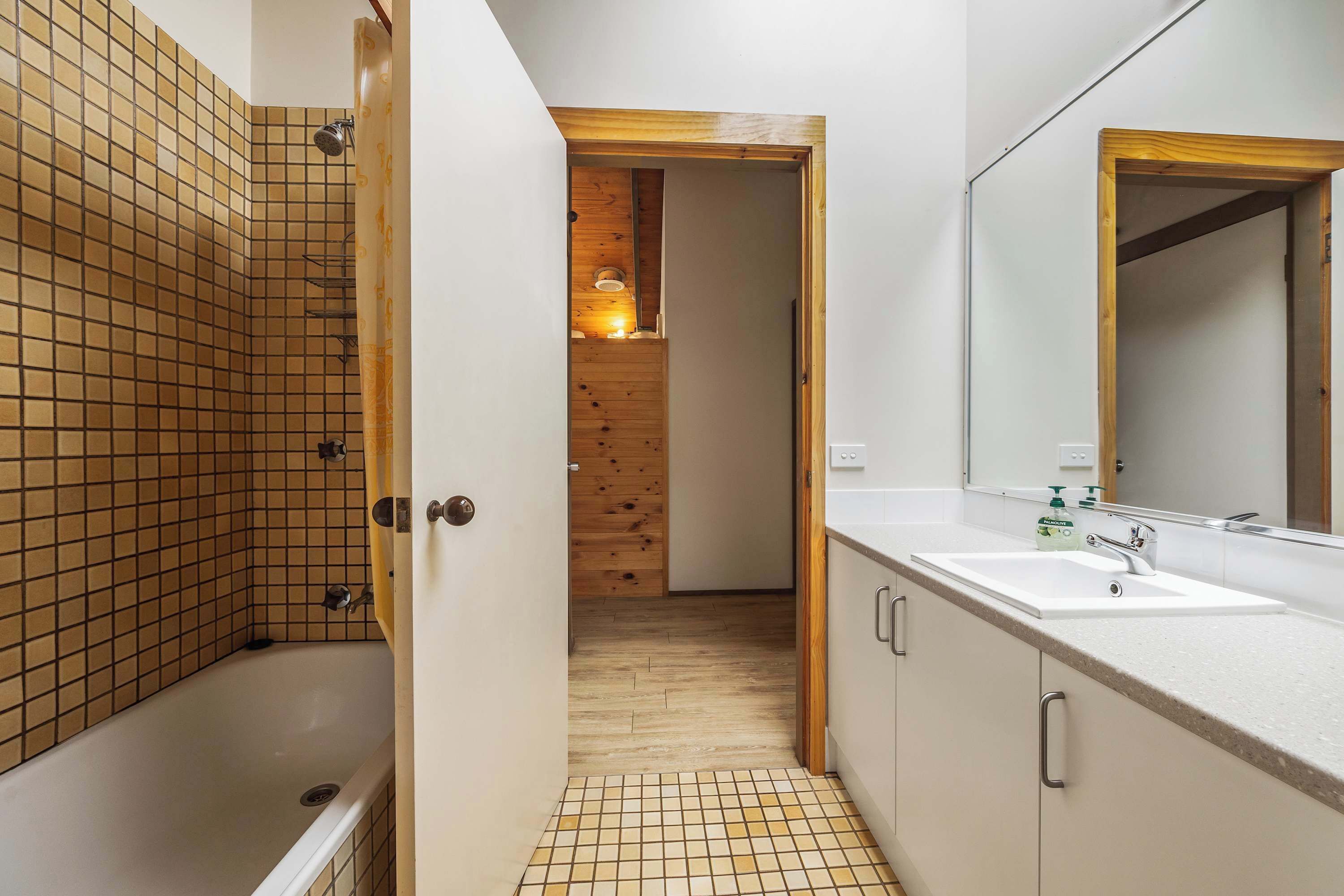 A modern bathroom with a bathtub, a sink, and a wooden door leading to another room.