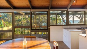 Una cocina moderna con ventanas amplias, una mesa de comedor de madera y vistas al exterior.