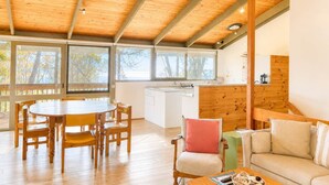 Una habitación amplia con techo de madera, una mesa de comedor con sillas, un sofá y una zona de cocina.