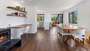 Eine moderne Küche mit eingebautem Herd, weißen Barhocker und einem Essbereich mit Holztisch und Stühlen.