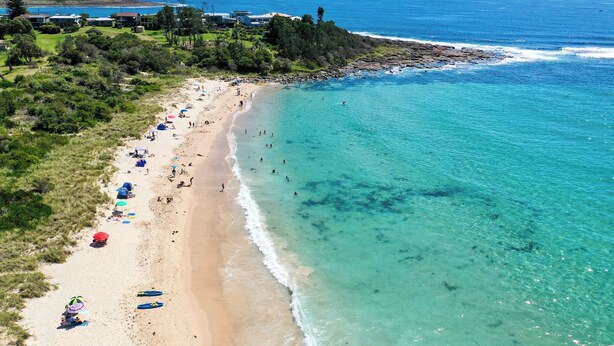 An aerial view of a beach with clear turquoise waters, a sandy shore, and several umbrellas and beach chairs. - Seaview Escape at Gannet (Bawley Point)