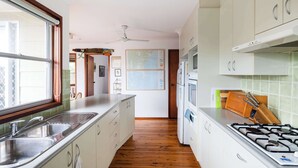 A kitchen with a gas stove, sink, and cabinets. - Seaview Escape at Gannet (Bawley Point)