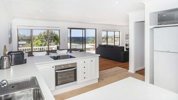 Una cocina moderna con una isla grande, armarios blancos y vistas al exterior.