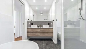 Un baño moderno con una bañera independiente, un tocador con un salpicadero a cuadros blanco y negro, y un box de ducha de vidrio.