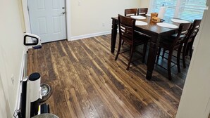 A dining area with a wooden table and chairs, a white door, and a window with blinds. - Cozy home in Milford/Harrington 
for relaxing stays! (Harrington)