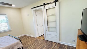 A room with a bed, a TV stand, a sliding door, and a window. - Cozy home in Milford/Harrington 
for relaxing stays! (Harrington)