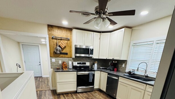 A modern kitchen with wooden flooring, white cabinets, a ceiling fan, and a built-in microwave. - Cozy home in Milford/Harrington 
for relaxing stays! (Harrington)