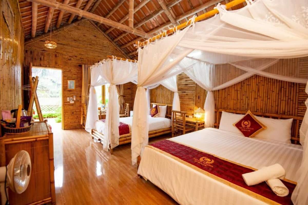 Una habitación con una cama grande, una cama más pequeña, un ventilador y techo de madera.