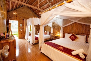 Una habitación con una cama grande, una cama más pequeña, un ventilador y techo de madera.