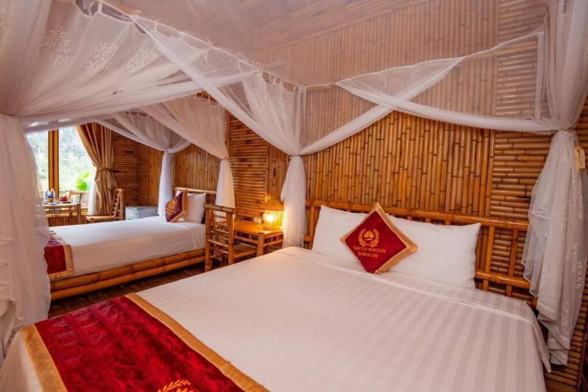 Una habitación con dos camas, cabecero de madera, almohada roja y dosel.