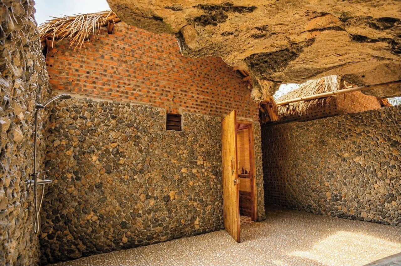 Una habitación con paredes de piedra, puerta de madera y techo de paja.