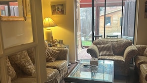 A living room with a glass coffee table, patterned sofas, a lamp, and a view of the outside. - Stylish Home with full Amenities (Uxbridge)
