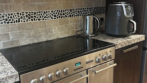A kitchen with a stainless steel stove, oven, and coffee maker on the countertop. - Stylish Home with full Amenities (Uxbridge)