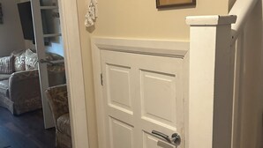 A hallway with a white door, a staircase, and three framed pictures on the wall. - Stylish Home with full Amenities (Uxbridge)