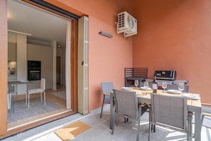 A dining area with a table set for two, a grill, and a sliding glass door leading to a kitchen. - Magical Menaggio Vista (Menaggio)