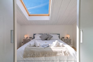 A bedroom with a skylight, a bed with pillows, a bedside table with a lamp, and a magazine on the bed. - Magical Menaggio Vista (Menaggio)