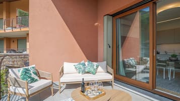 Un balcon équipé d’un canapé, de chaises, d’une table et d’une porte-fenêtre coulissante donnant sur un espace intérieur.