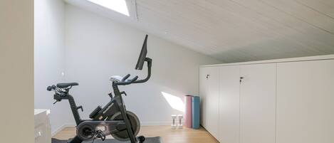 A room with a ceiling fan, a standing fan, a window, and a door.