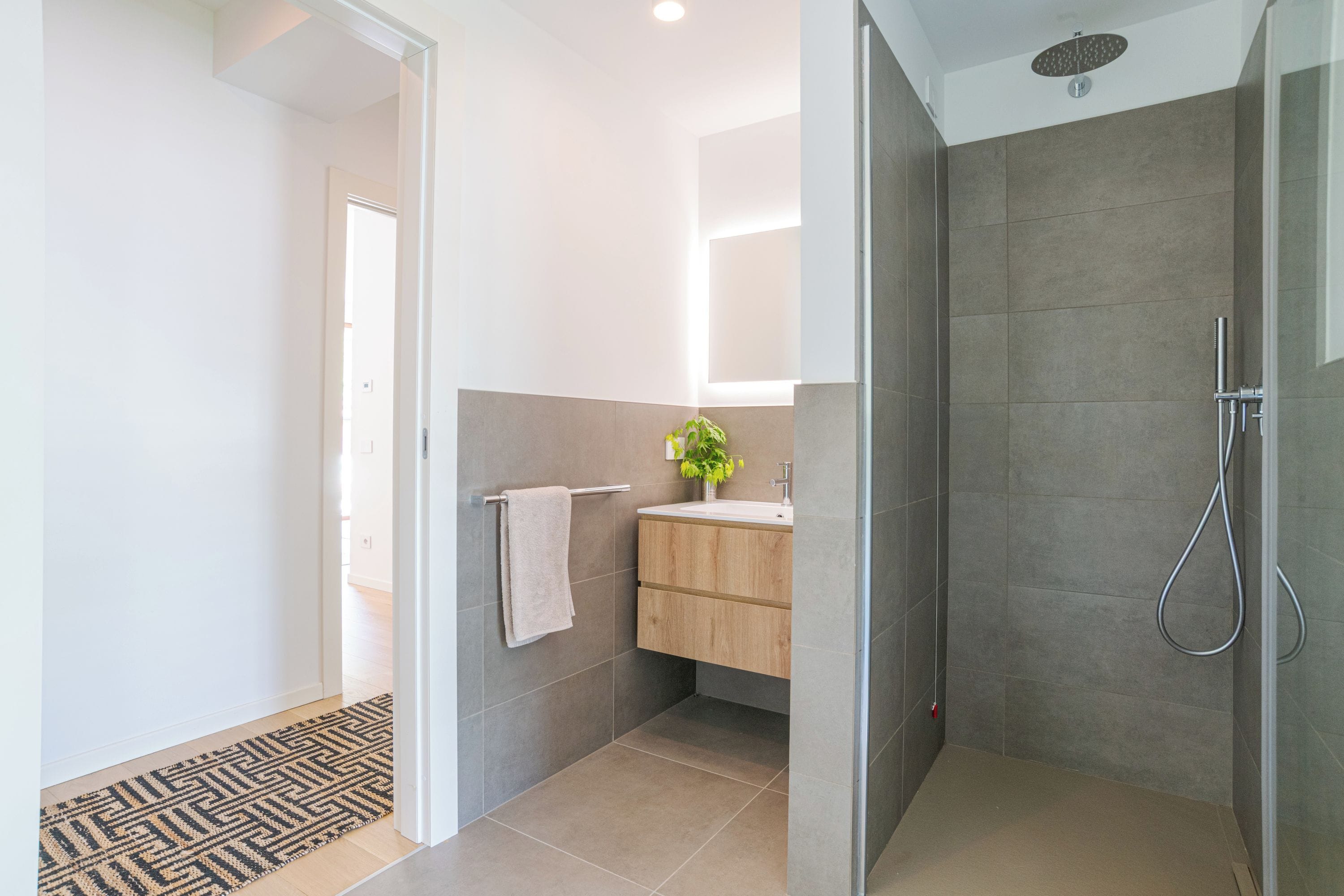 Ein modernes Badezimmer mit Dusche, Waschbecken und Handtuchhalter.