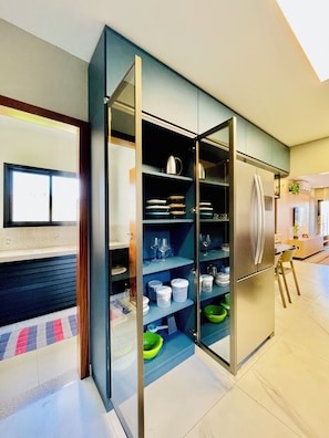 A modern kitchen with a built-in refrigerator, open shelving with dishes, and a dining area with a bar stool. - 3-bedroom apartment with a suite, comfortable, quiet, and well located (Aracruz)