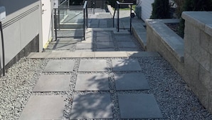 A modern building with a stone pathway leading to a gated entrance. - Room-brand new 2 Bedrooms (District of North Vancouver)