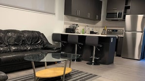 A modern kitchen with a black countertop, stainless steel appliances, and a black leather sofa. - Room-brand new 2 Bedrooms (District of North Vancouver)