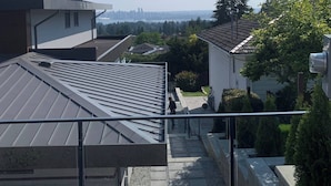 A residential area with modern houses, a clear sky, and a distant city skyline. - Room-brand new 2 Bedrooms (District of North Vancouver)