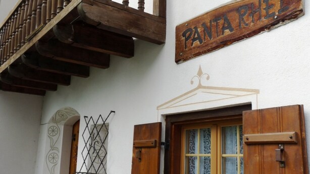 Un bâtiment doté d’un balcon en bois, d’une porte ornée d’un vitrail et d’une enseigne sur laquelle on peut lire « PANTARHEI ».