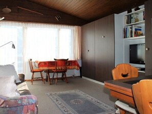 Ein Wohnzimmer mit Essbereich, einer Bücherregal und einem Fernseher.