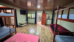 Un dormitorio con literas, un escritorio, un televisor y una ventana con cortinas.