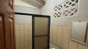 Un baño con inodoro, lavabo, ducha y un panel decorativo en la pared.