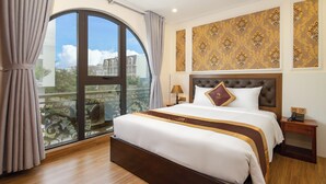 A hotel room with a large window, a bed with a headboard, a bedside table, and a wall with patterned wallpaper. - Seven Sea Villa Hotel & Apartment (Da Nang)