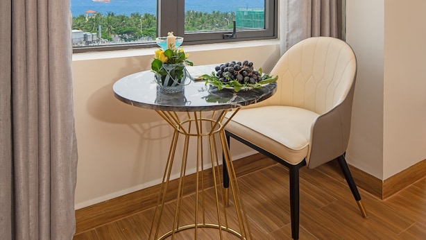 A room with a view of the sea, a round table with a chair, and a window with curtains. - Seven Sea Villa Hotel & Apartment (Da Nang)