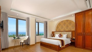 A hotel room with a large bed, a desk, and a view of the sea. - Seven Sea Villa Hotel & Apartment (Da Nang)