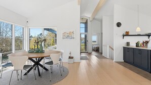 Ein modernes Interieur mit Essbereich, Küche und großen Fenstern.