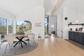 Ein modernes Interieur mit Essbereich, Küche und großen Fenstern.