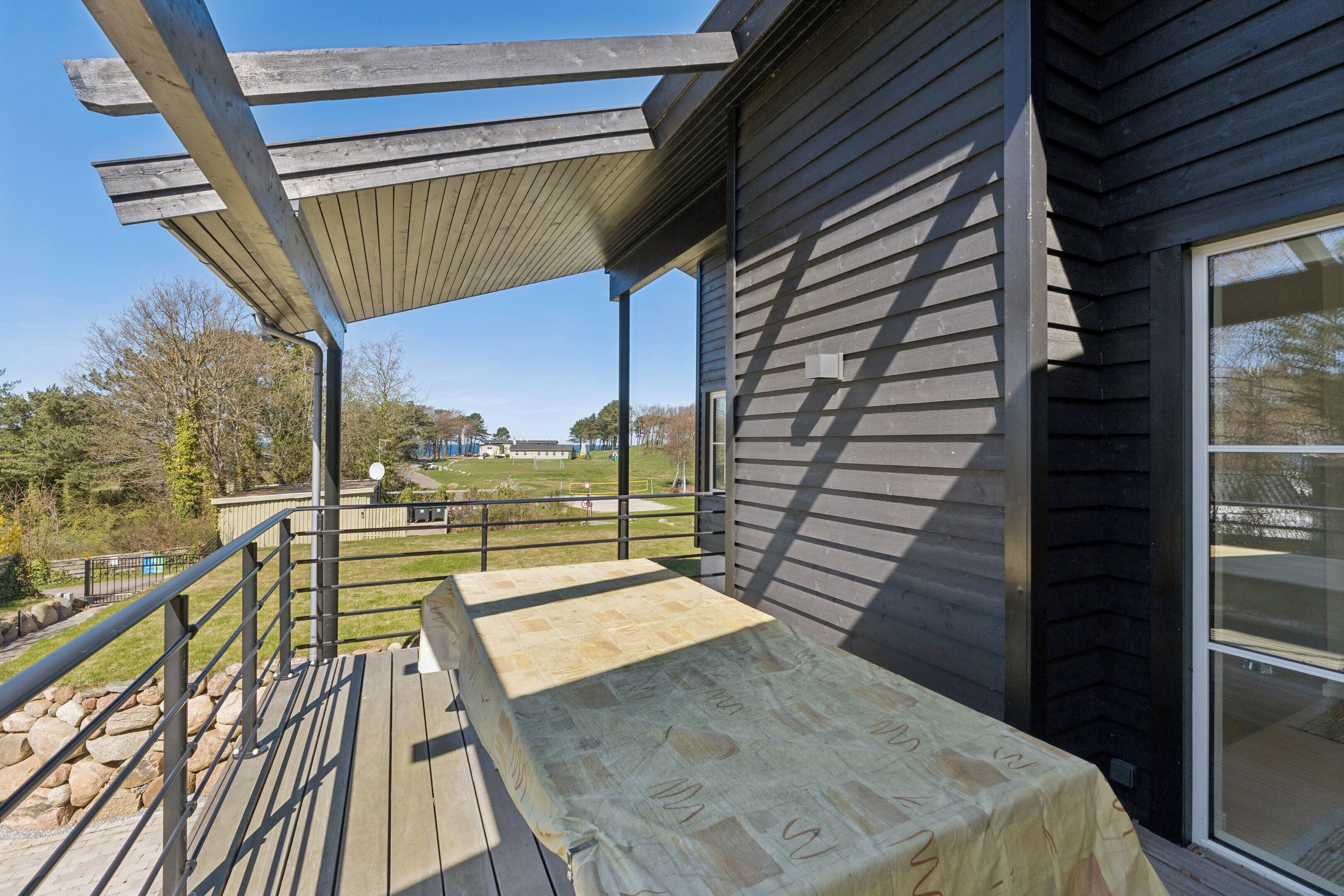 A covered deck with a view of a grassy area and a building in the background.