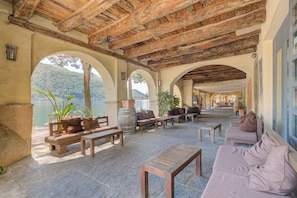 An outdoor patio area with stone flooring, wooden furniture, and a view of a lake. - Palazzo Gritti Papavero, Morcote, Switzerland (Morcote)
