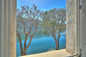 A view through an open window with a clear sky, trees, and a body of water. - Palazzo Gritti Papavero, Morcote, Switzerland (Morcote)