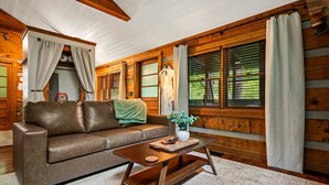 A wooden cabin interior with a brown leather sofa, a wooden coffee table, and a green plant. - New Cozy Spa Cabin! Hot Tub, Sauna, Jacuzzi! 20% Off-New Listing Promotion! (Sevierville)