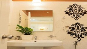 A bathroom with a sink, mirror, potted plant, and decorative wall patterns. - Hotel Granton By Carlton Suites (Hyderabad)