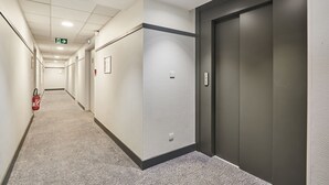 A hallway with a fire extinguisher, a door, and a light switch. - Studio Rénové + Climatisé | Wi-Fi Gratuit ! (Aix en Provence)