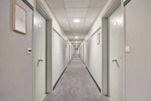 A long, narrow hallway with doors on both sides, each marked with a number. - Studio Rénové + Climatisé | Wi-Fi Gratuit ! (Aix en Provence)