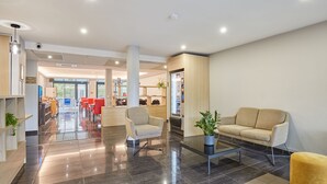 A modern hotel lobby with a reception desk, seating area, and a dining space in the background. - Studio Rénové + Climatisé | Wi-Fi Gratuit ! (Aix en Provence)
