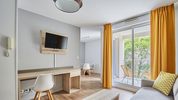 Un soggiorno moderno con divano, tavolino e TV a parete. È presente anche una zona pranzo con sedie e tavolo.