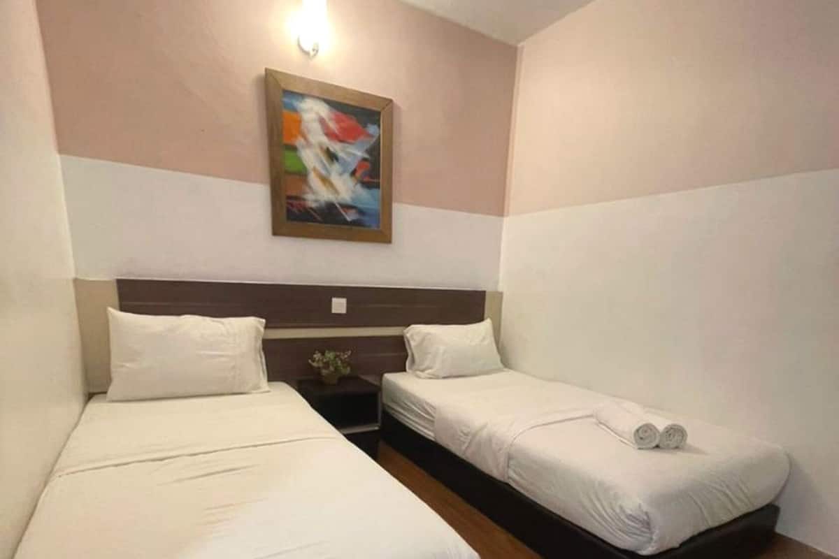 A hotel room with two beds, a nightstand, a painting on the wall, and a wooden floor.