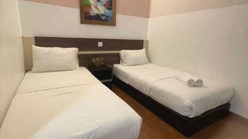 A hotel room with two beds, a nightstand, a painting on the wall, and a wooden floor.