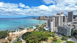 Paisagem costeira urbana com edifícios altos, praia e céu claro.